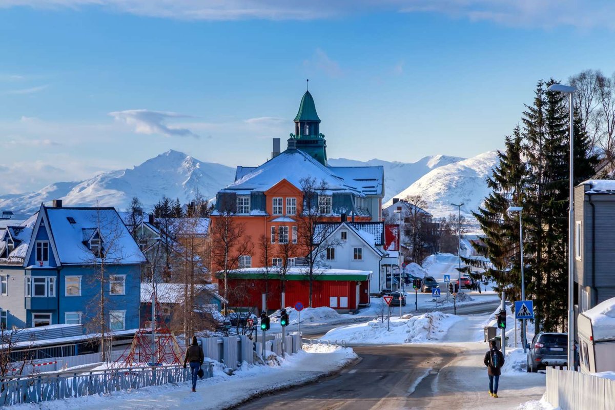 A winter view of downtown Tromsø with colorful houses and mountain scenery in the background.