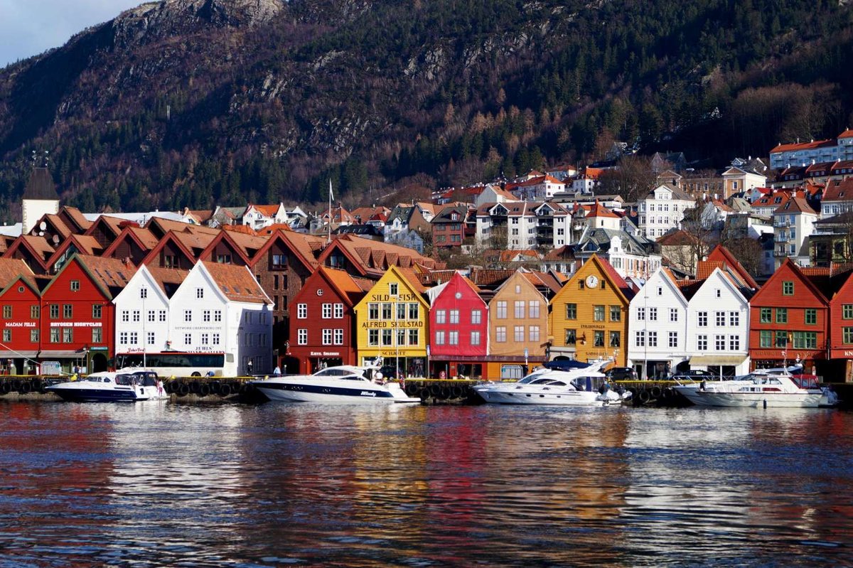 Colorful wooden houses along Trondheim’s waterfront with moored boats.
