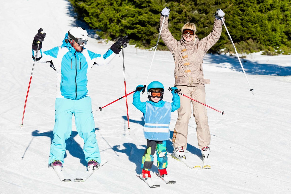 A family with a child enjoys a sunny slope in Hafjell—safe, family-friendly skiing.