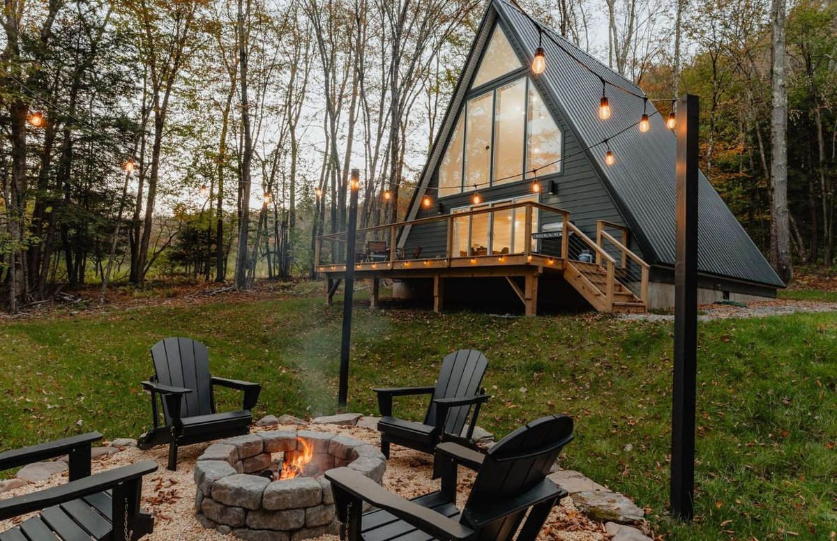 A modern glamping cabin in the forest with a fire pit and cozy lighting.