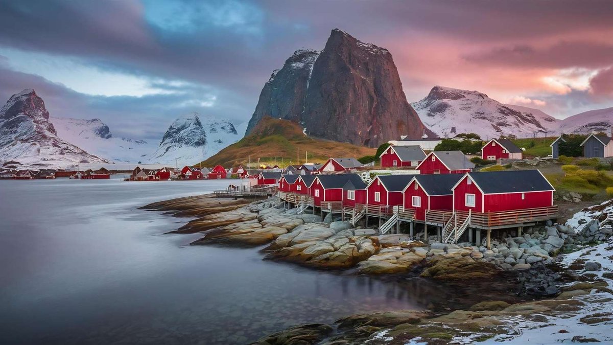 Guest cabins in the Lofoten Islands are located on the shore with views of the mountains and sea.