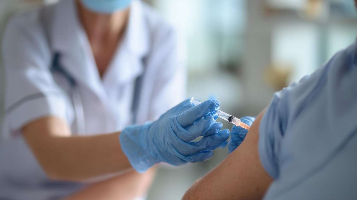 A healthcare worker administers an injection to a patient’s shoulder.