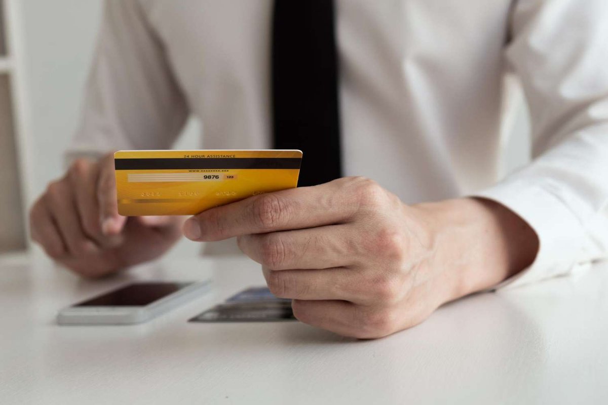 Person holding a bank card over a smartphone.
