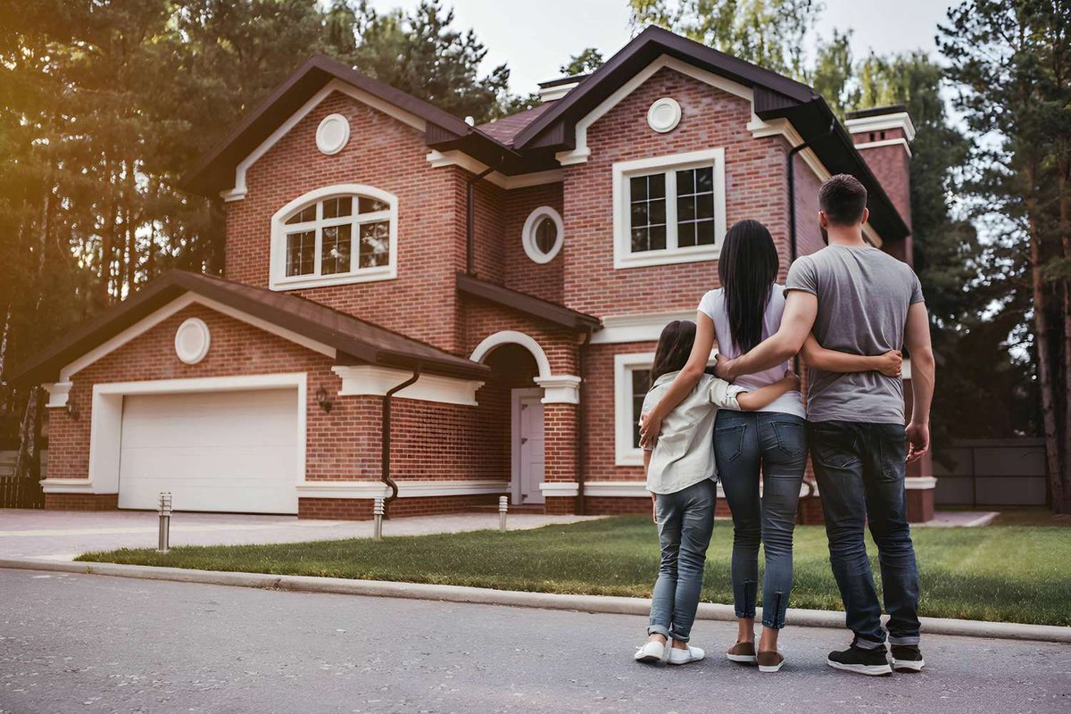 A family stands in front of a rented countryside cottage surrounded by forest.
