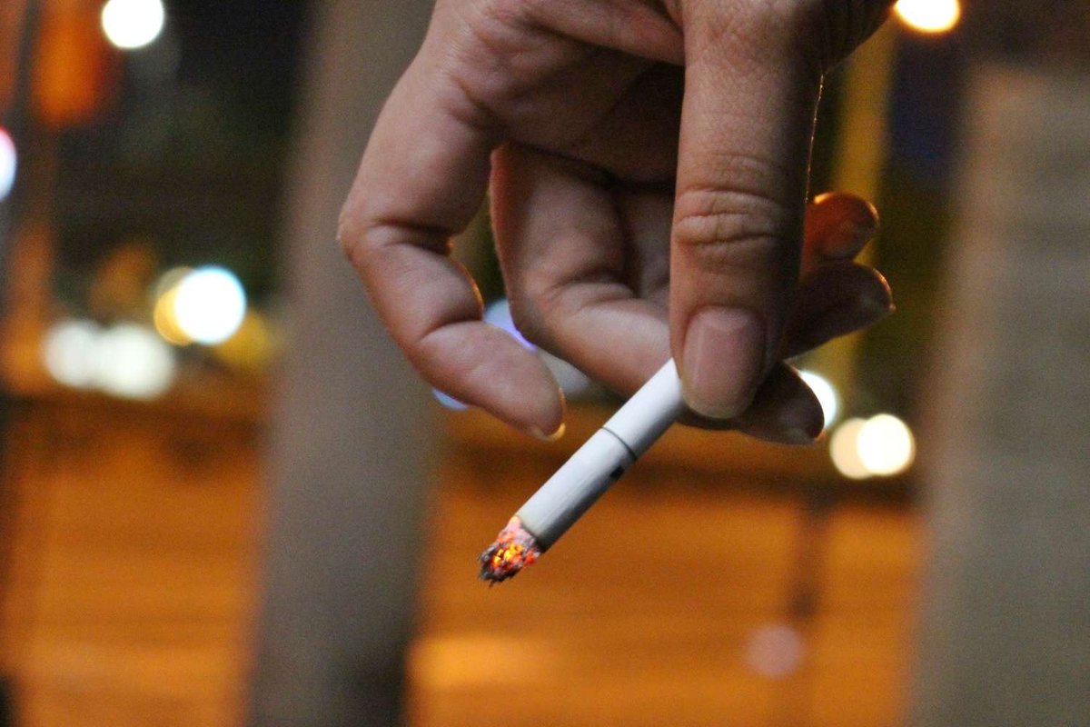 A person holding a lit cigarette in their hand.