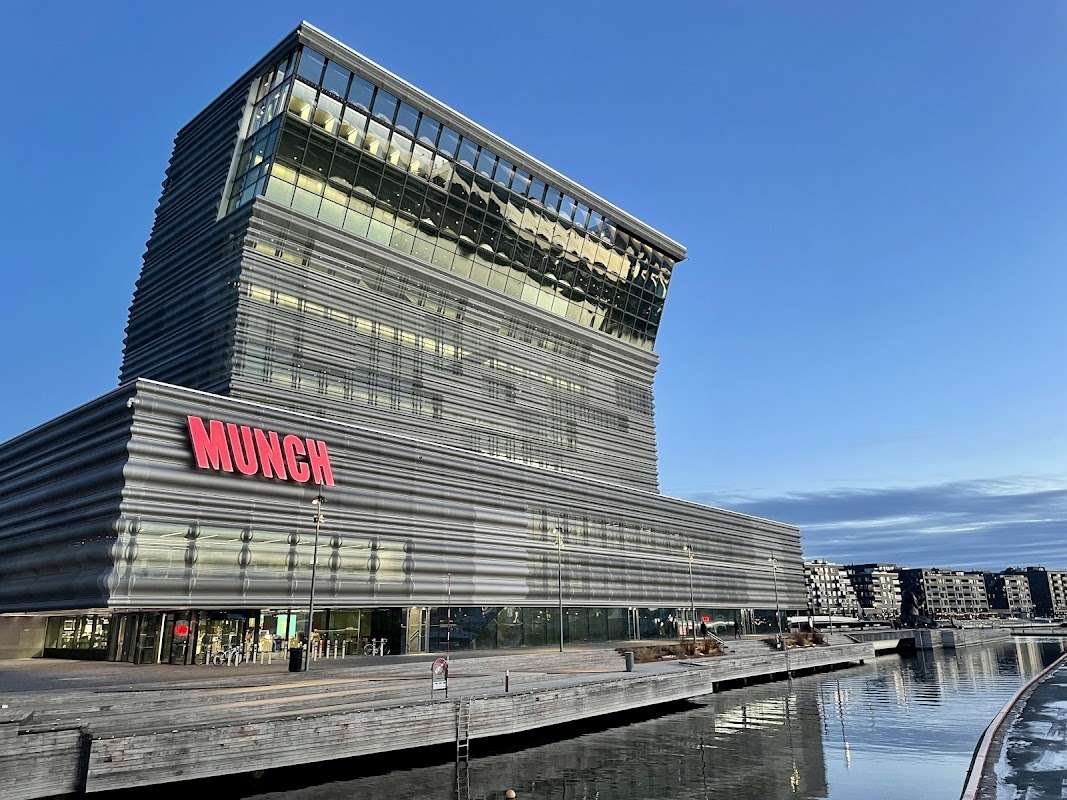 The modern building of the Munch Museum in Oslo, located on the waterfront and reflecting in the water at sunset.