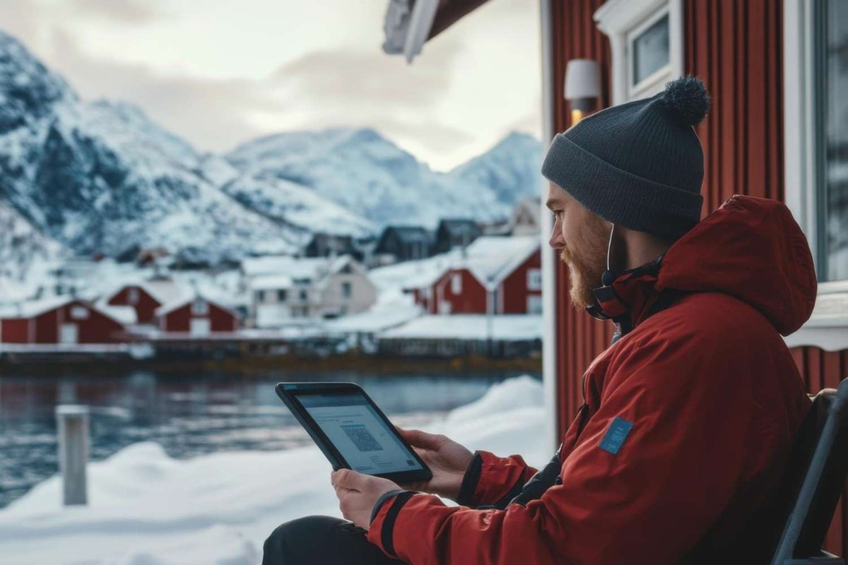 A man using a tablet against the backdrop of a snowy waterside village.