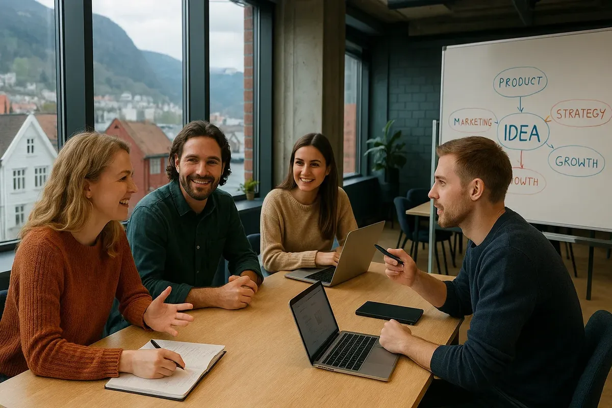 A group of young professionals in a Norwegian co-working space discussing startup ideas with laptops and whiteboards.